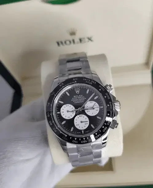 A close-up of a Rolex Daytona with a black dial and three subdials, made of stainless steel, displayed on a cushioned holder inside an open Rolex box.
