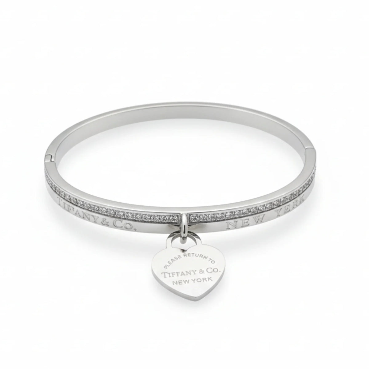 A silver Bracelete Bangle Return to Tiffany with a row of small diamonds and a heart-shaped charm engraved "Please return to Tiffany & Co. New York"—a joia de luxo for any collection.