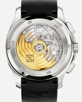 A close-up of the Relógio Patek Aquanaut reveals its detailed silver and gold-toned mechanical movement through a transparent case back, making it the perfect relógio executivo on an elegant black strap.