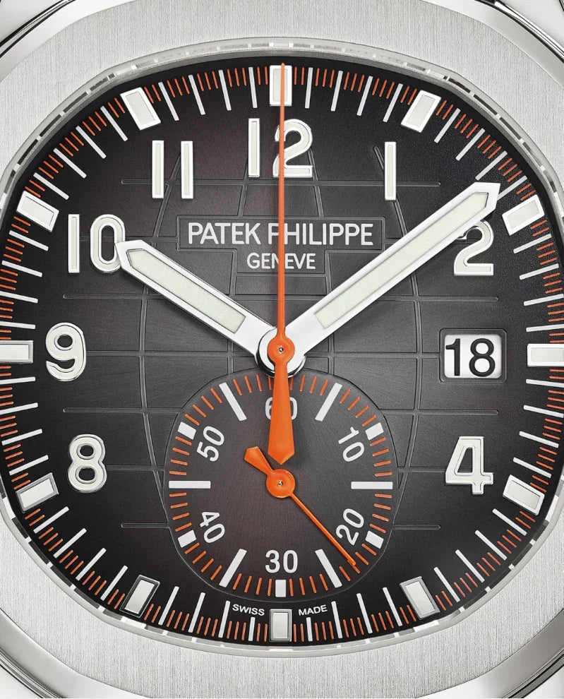 Close-up do Relógio Patek Aquanaut com mostrador preto, números brancos em destaque, ponteiros brancos e laranja, janela de data às 3h e subdial de segundos às 6h—um verdadeiro relógio de luxo com detalhes sofisticados.